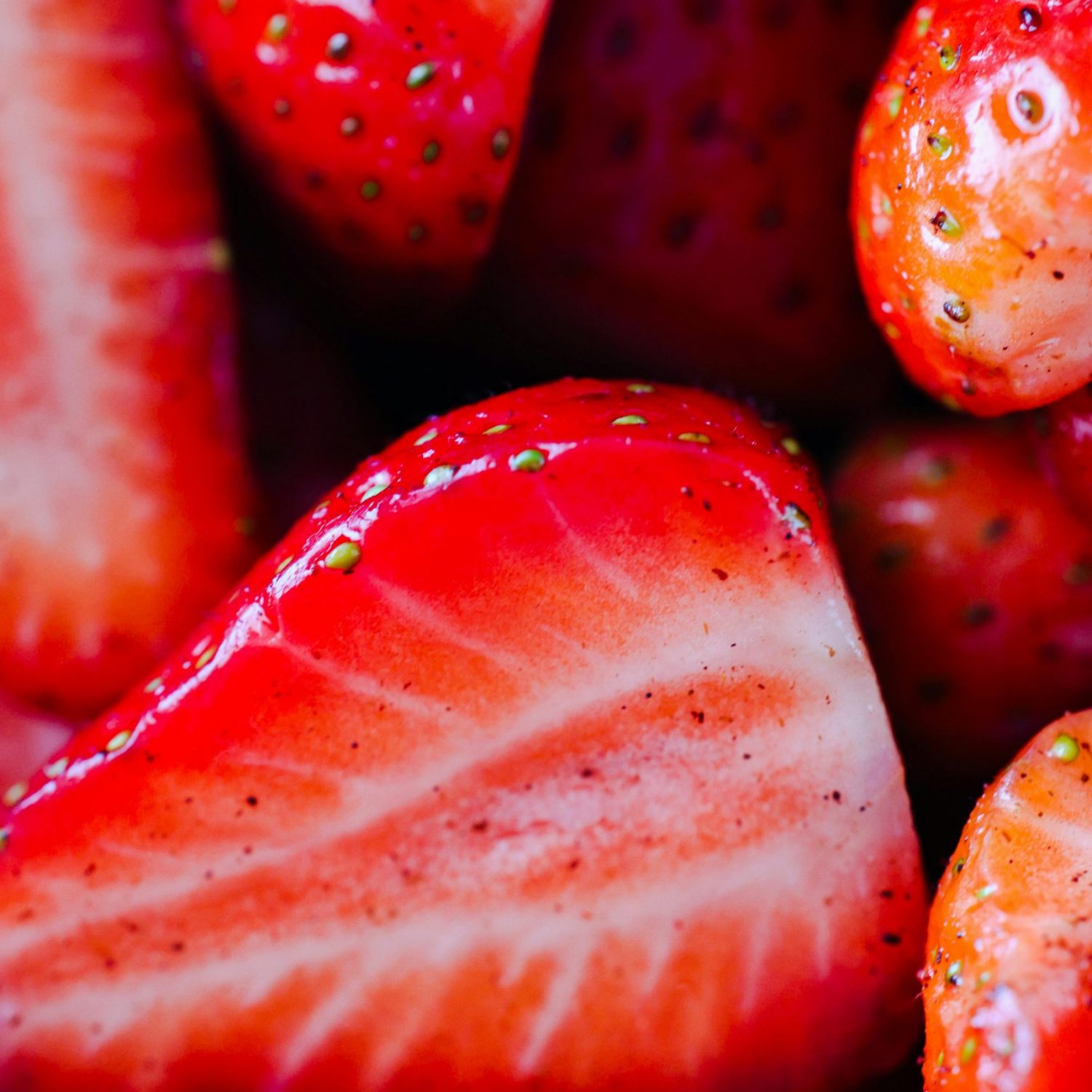 Vibrant red strawberries shown in close-up, including halves, highlighting freshness and texture.